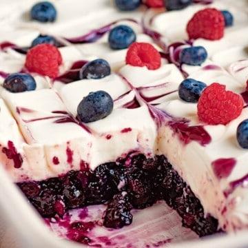 Blueberries and raspberries on whipped filling and sliced blueberry jello in white dish.