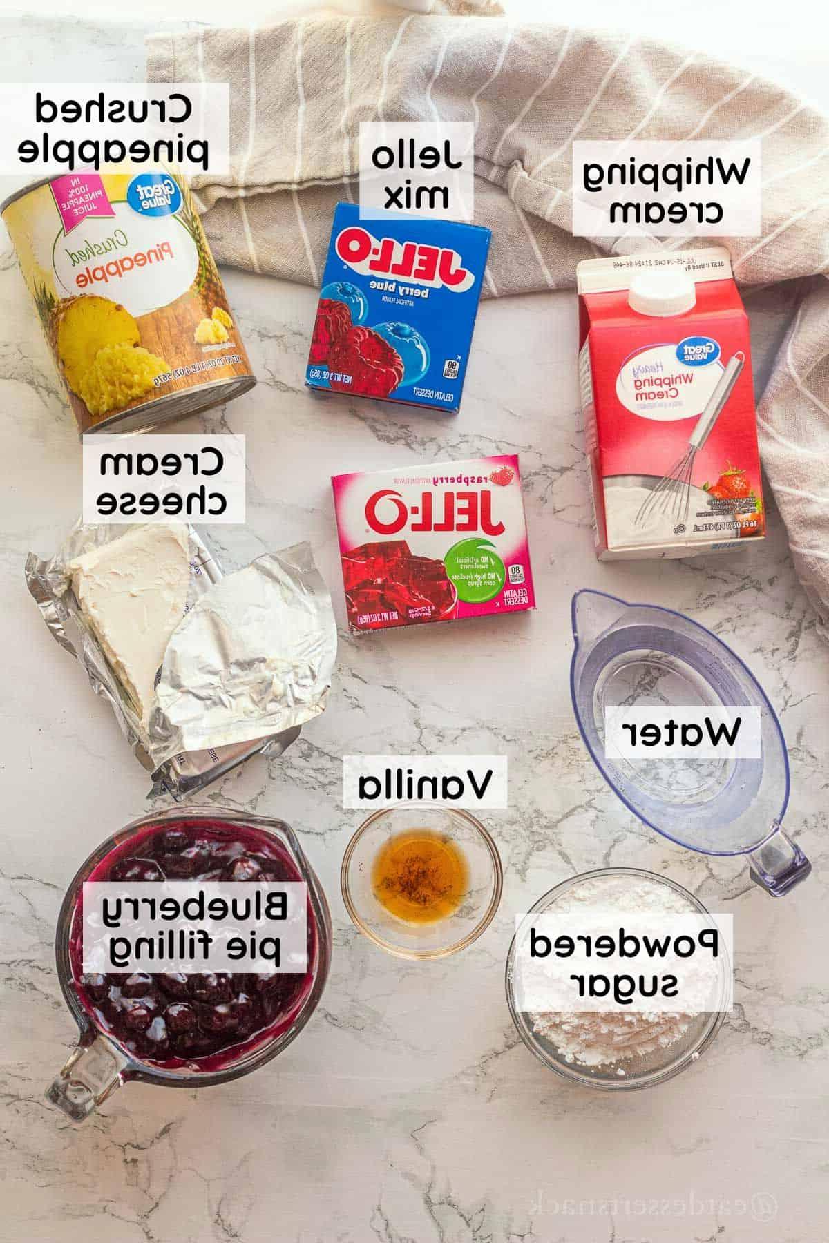 Labeled ingredients for blueberry jello salad in glass dishes on marble countertop.