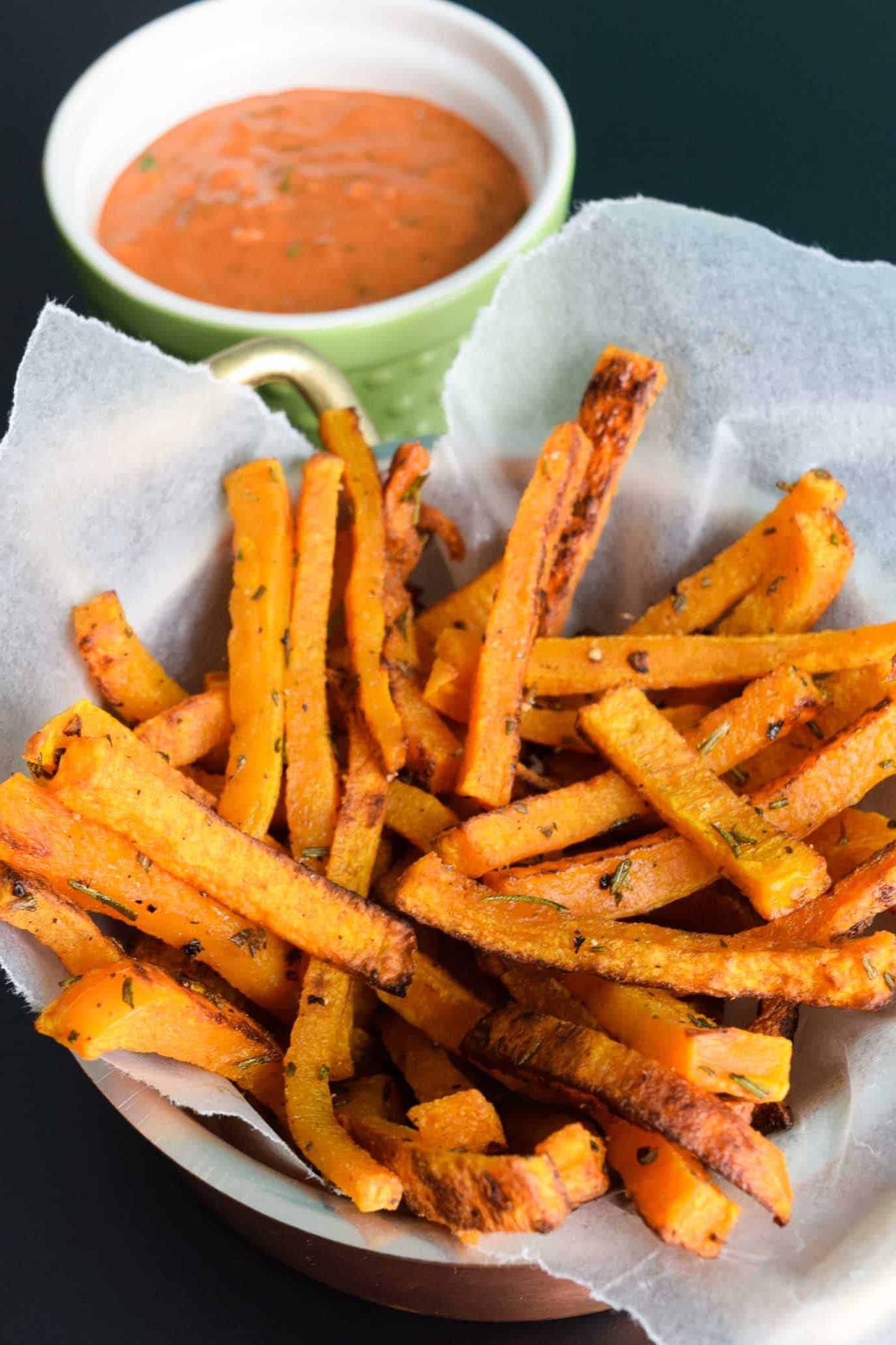 Butternut Squash Fries in waxed paper lined bowl with magic sauce in green bowl behind