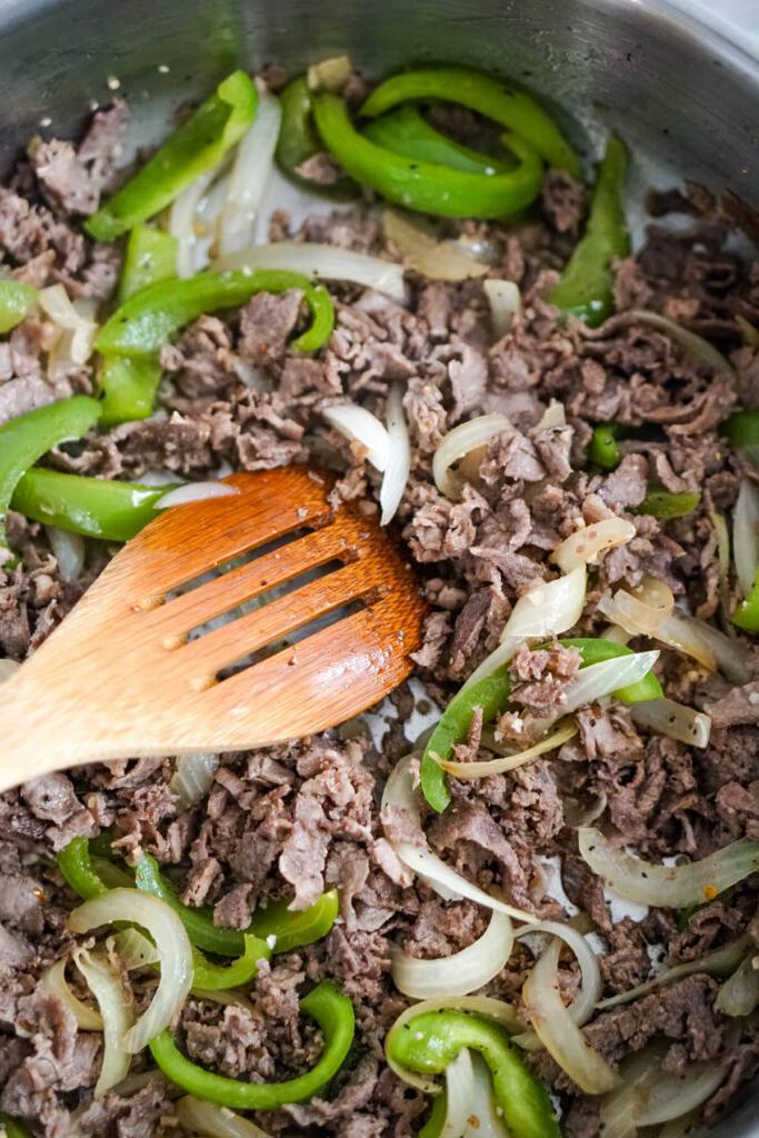 The steaks, onions, and peppers and stirred together with a wooden spoon.